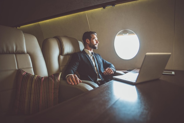 Un uomo d'affari che guarda lontano mentre è seduto in un jet aziendale.