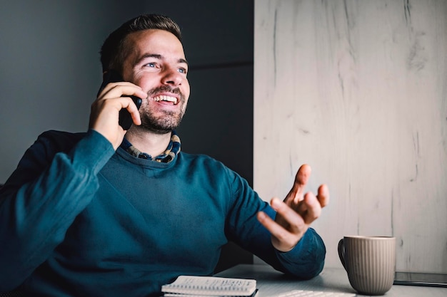 Un uomo d'affari che parla al telefono mentre è seduto nel suo ufficio di notte