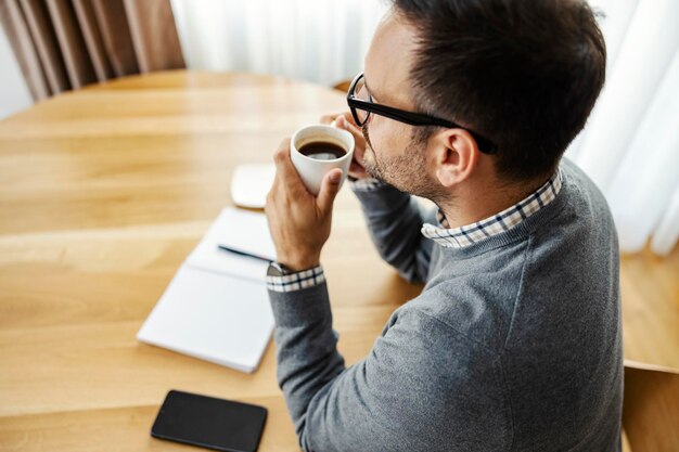 Un uomo d'affari che si gode il suo caffè mentre lavora da casa in remoto