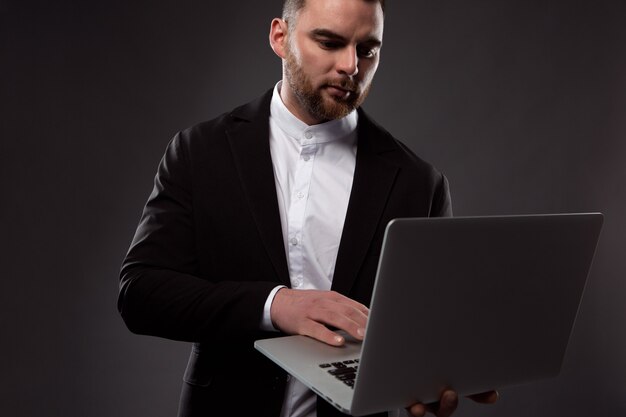 un uomo d'affari concentrato lavora con un laptop che tiene in mano.