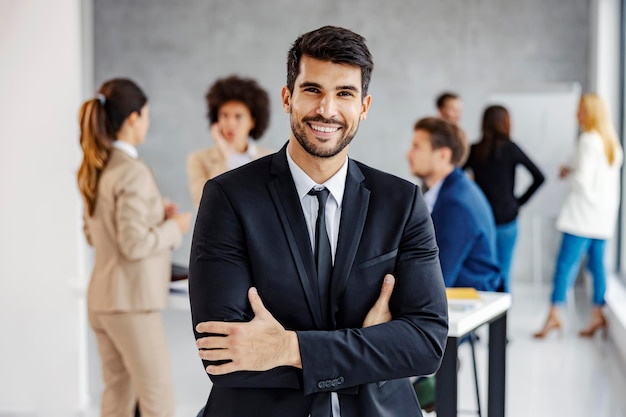 Un uomo d'affari di successo nell'ufficio pieno di uomini d'affari che sorridono alla macchina fotografica