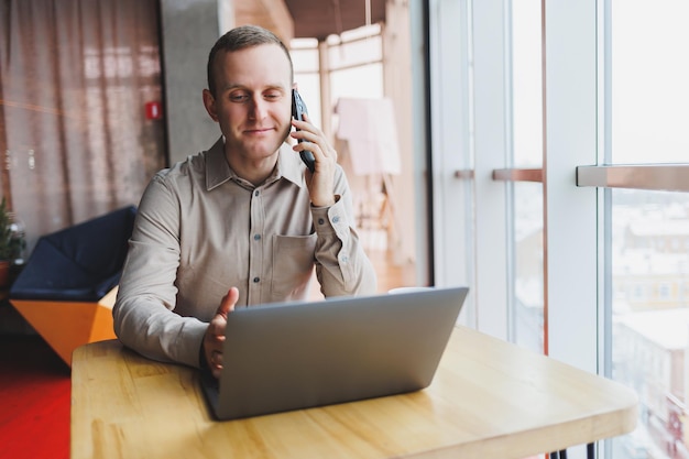 Un uomo d'affari di successo si siede in un caffè di lavoro e lavora su un progetto importante Uomo d'affari sta digitando su un computer portatile Uomo d'affari utilizzando il computer portatile in caffè