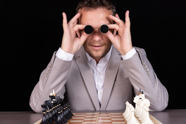 Un uomo d'affari esprime le emozioni con le mani e il viso con le pedine degli scacchi con umorismo