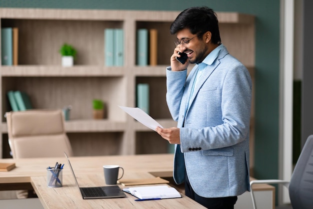 Un uomo d'affari indiano che discute di documenti al telefono in ufficio