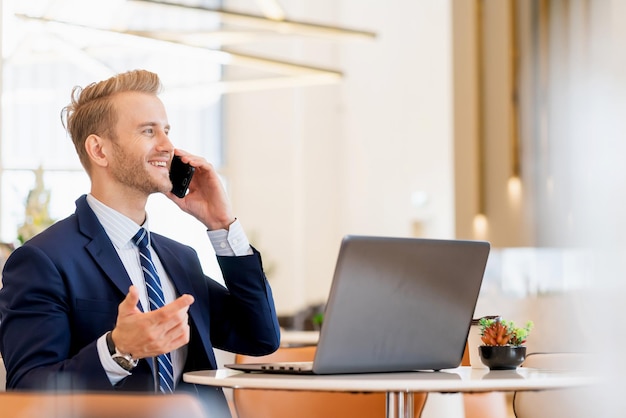 Un uomo d'affari sorridente che parla al cellulare in ufficio
