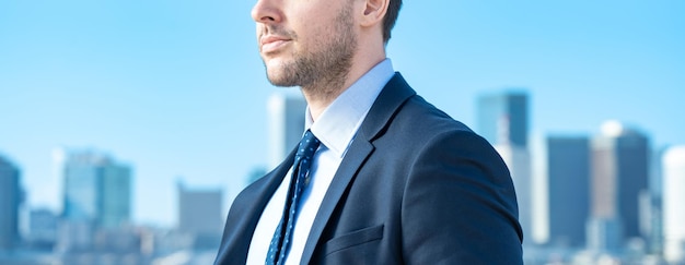 Un uomo d'affari sullo sfondo del cielo azzurro e degli edifici