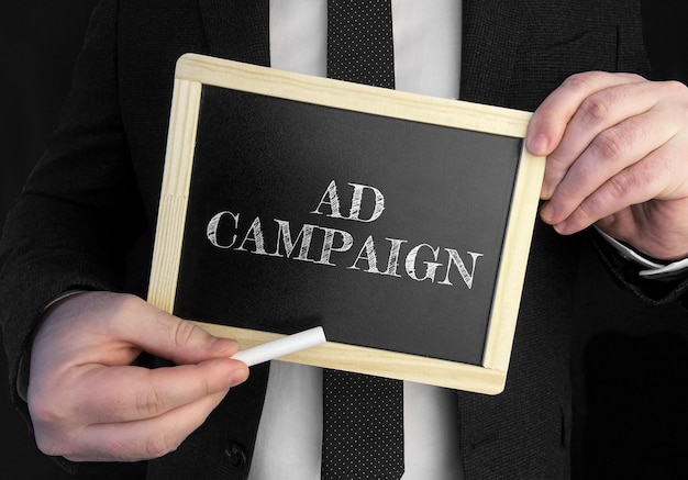 Un uomo d'affari tiene in mano una lavagna con testo Campagna pubblicitaria