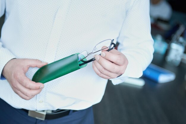 Un uomo d'affari tira fuori gli occhiali da una speciale custodia in pelle. Accessori da uomo per riporre oggetti in vera pelle.