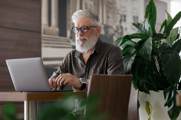 Un uomo dai capelli grigi incredibilmente bello ed elegante di cinquant'anni che lavora con un laptop