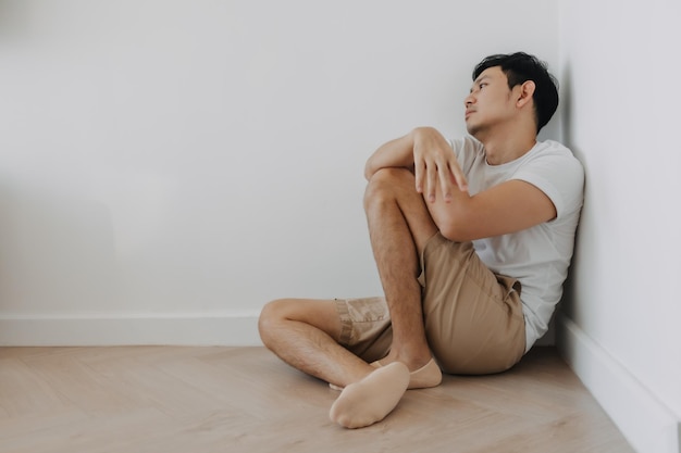 Un uomo deprimito e solitario si siede all'angolo della stanza.