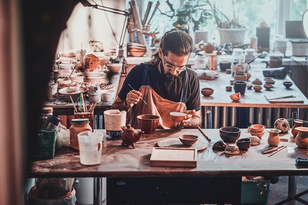 Un uomo diligente sta mettendo dell'argilla colorata nel suo nuovo vaso fatto a mano.