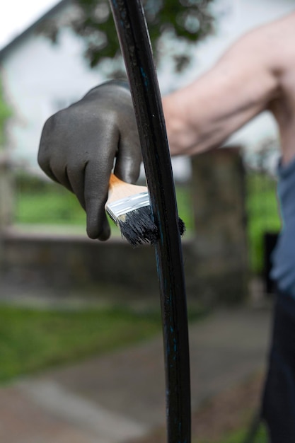 Un uomo dipinge un arco con un pennello Dipinge nel suo cortile L'uomo in guanti Vernice nera Local focus