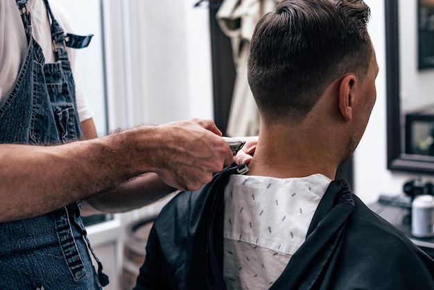 Un uomo è in giro in un salone di bellezza. Taglio di capelli e styling nel negozio di barbiere. Cura maschile per barba e capelli.