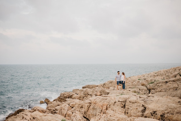 Un uomo e la sua ragazza si stanno abbracciando sulla costa rocciosa del mare in Spagna