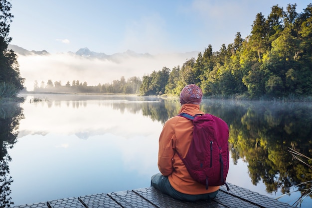 Un uomo è seduto a suo agio in riva al lago calmo. Vacanza relax