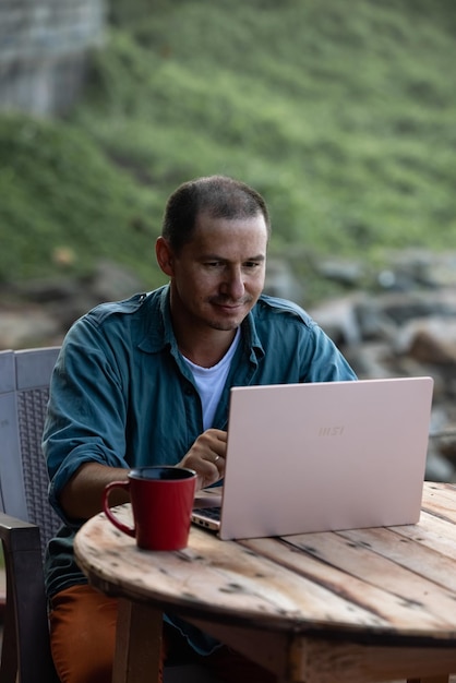 Un uomo è seduto a un tavolo con sopra un laptop.