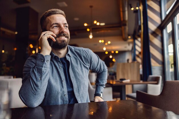 Un uomo è seduto al bar e sta conversando al telefono