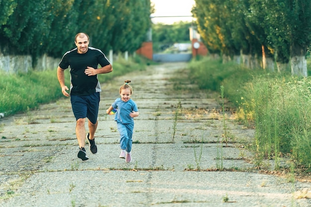 un uomo e una bambina si divertono a correre lungo il vicolo del parco in estate