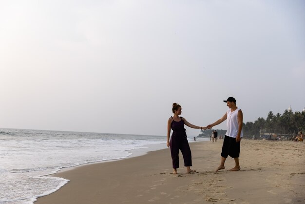 Un uomo e una donna ballano sulla spiaggia, uno di loro si tiene per mano.