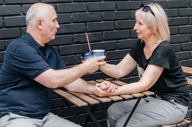 un uomo e una donna bevono caffè vicino a un muro bianco e nero