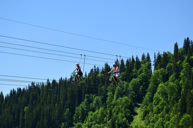 Un uomo e una donna cavalcano un'attrazione in bicicletta su funi da terra Sullo sfondo