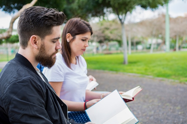 Un uomo e una donna che leggono un libro seduto nel parco.