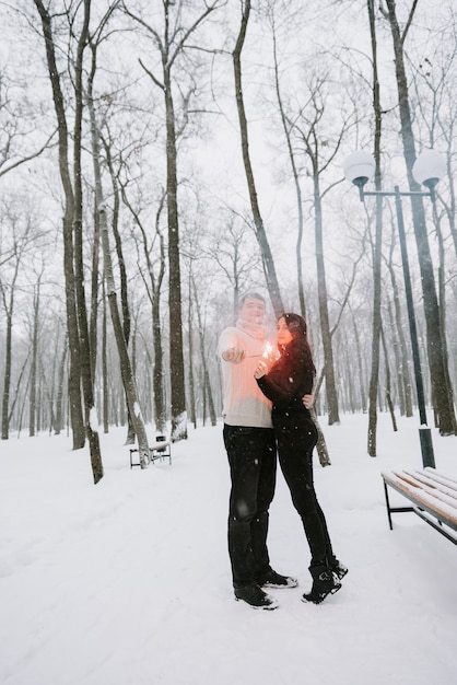 Un uomo e una donna con le stelle filanti sullo sfondo di un bosco innevato in una nevicata