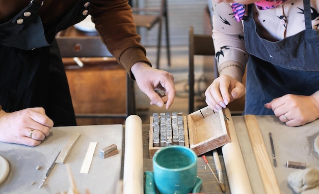 Un uomo e una donna scelgono le lettere da stampare su argilla bagnata Data concettuale fatta a mano nel laboratorio di ceramica