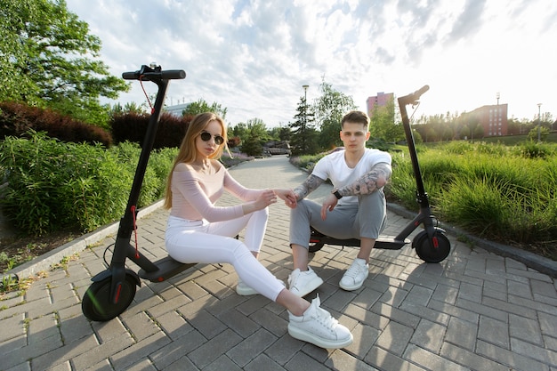 Un uomo e una donna si siedono su scooter elettrici nel parco