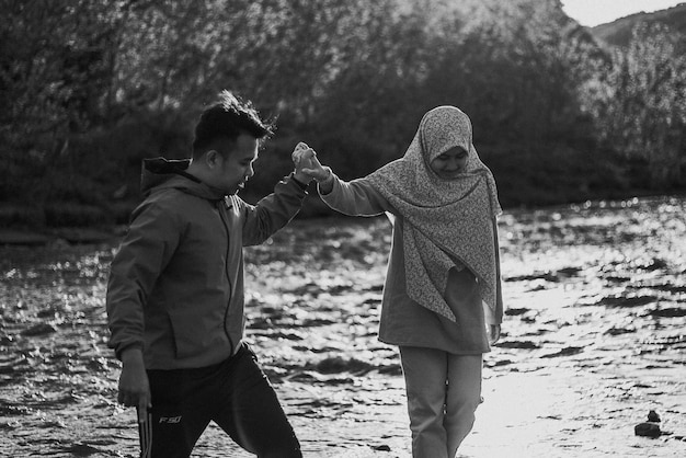 Un uomo e una donna si tengono per mano in un fiume.