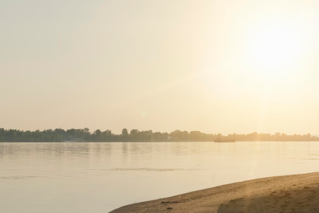 Un uomo e una donna sono in piedi su una spiaggia di fronte a un fiume e il sole sta tramontando.