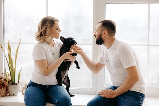 Un uomo e una donna sono seduti alla finestra con un cane di nome Bia.