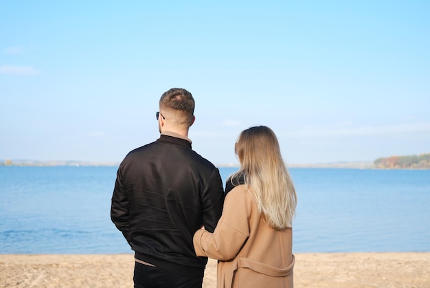 Un uomo e una donna stanno fianco a fianco sulla spiaggia e guardano verso il lago