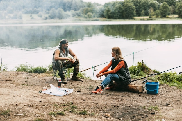 Un uomo e una donna stanno pescando sulla riva di un lago o di un fiume una coppia sposata trascorre del tempo insieme