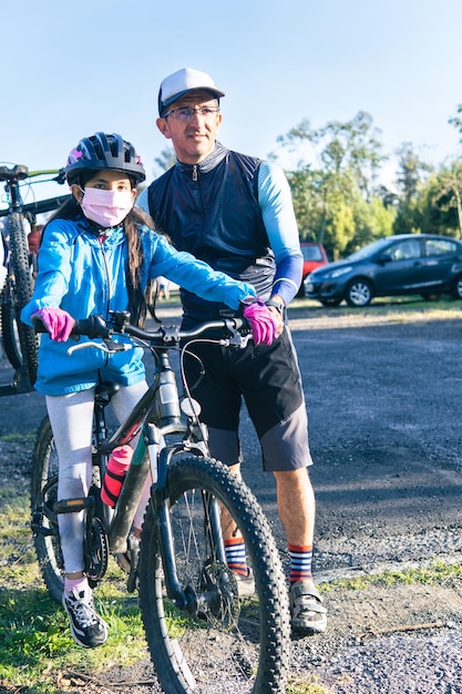 Un uomo e una ragazza che indossano una maschera facciale stanno accanto alle loro biciclette.