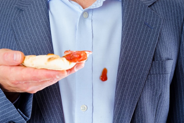 Un uomo elegante e irriconoscibile che tiene una fetta di pizza e si macchia i vestiti di salsa. isolato