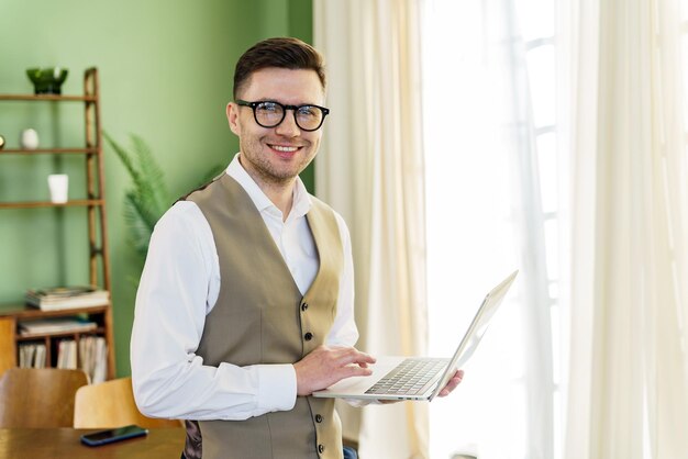 Un uomo esperto di affari con un giubbotto e una camicia tiene un portatile la sua posizione fiduciosa significa il suo