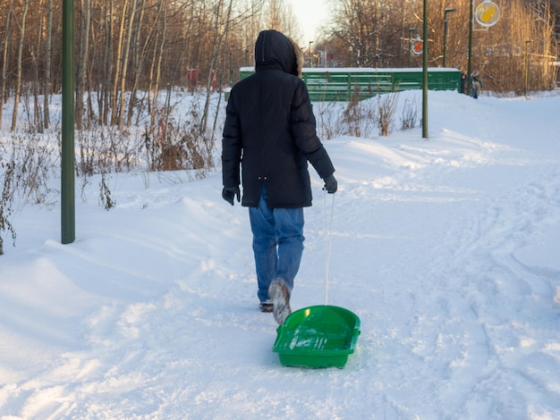 Un uomo fa rotolare una slitta lungo una strada invernale