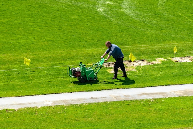 Un uomo falcia il prato nello stadio di calcio alla vigilia della partita