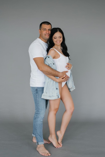 Un uomo felice abbraccia la sua ragazza incinta e guarda nella telecamera Il marito amorevole abbraccia delicatamente la moglie incinta in attesa di un bambino