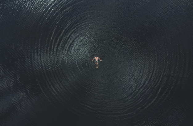 Un uomo giace sulla superficie dell'acqua Galleggiabilità umana Veduta aerea In armonia con l'elemento
