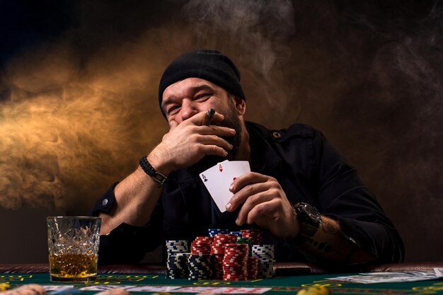 Un uomo gioca a poker con un sigaro e un whisky un uomo mostra due carte in mano vincendo tutti i chi...