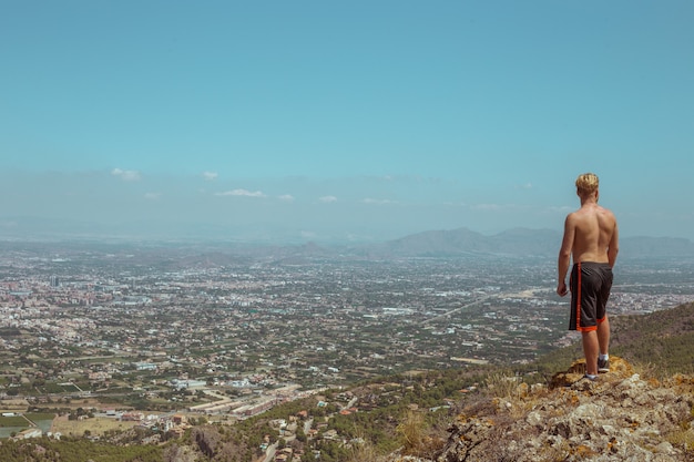 Un uomo guarda la città dall'orlo della scogliera