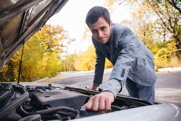 Un uomo guarda sotto la quota di un'auto rotta.