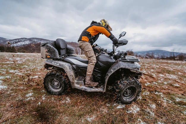 Un uomo guida un atv nella deriva di fango guidando un quad atv nel fango e nella neve