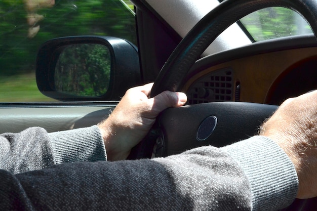 un uomo guida un'auto e tiene il volante