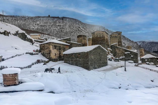 Un uomo guida un cavallo nel villaggio georgiano innevato di Ushguli Svaneti