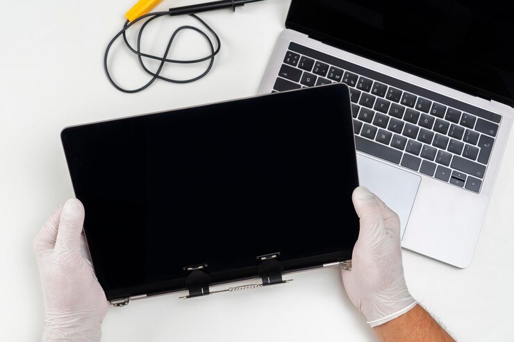 Un uomo ha sostituito un monitor rotto su un laptop e lo tiene tra le mani in una stanza bianca e chiara