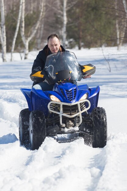 Un uomo in abiti invernali in sella a una motoslitta nella foresta invernale