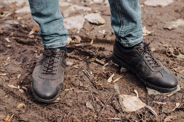 Un uomo in abito blu lega i lacci delle scarpe su scarpe brogue in pelle marrone su un parquet di legno